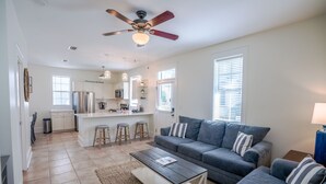 A modern living room with a grey sofa, a coffee table, and a ceiling fan. - Seagrove 30A Beach Bungalow with Pool and Hot Tub (Santa Rosa Beach)