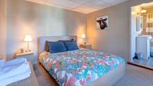 A hotel room with a bed, two bedside tables with lamps, a bathroom visible through an open door, and a wall-mounted picture. - Candy Bar, Apt #8
One Bedroom with pull out (Hershey)