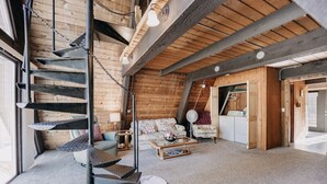 A loft-style room with a spiral staircase, a sofa, a coffee table, and a washing machine.