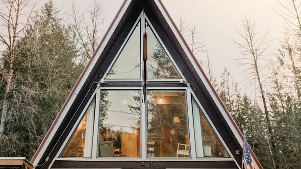 A triangular building with large windows, surrounded by trees.
