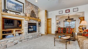 A cozy living room with a stone fireplace, a television, and a comfortable seating area. - Premiere 2br Townhome - Shuttle To Slopes. Kids Ski Free! 2 Bedroom Condo by RedAwning (Keystone)