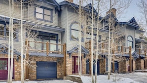A row of townhouses with stone facades, blue trim, and a prominent number '1947' on the front door. - Premiere 2br Townhome - Shuttle To Slopes. Kids Ski Free! 2 Bedroom Condo by RedAwning (Keystone)