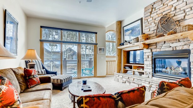A cozy living room with a fireplace, large windows, and a comfortable seating area. - Premiere 2br Townhome - Shuttle To Slopes. Kids Ski Free! 2 Bedroom Condo by RedAwning (Keystone)