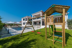 Et boligområde med en swimmingpool, et trælegehus og et toetagers hus.