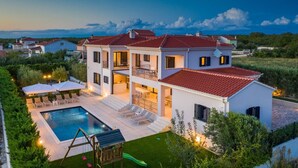 A two-story house with a swimming pool, outdoor seating, and a well-maintained garden.