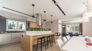 A modern kitchen with a central island, bar stools, and pendant lighting.