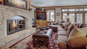 A cozy living room with a stone fireplace, a television, and comfortable seating. - 4br Ski In/ski Out The Top Of Bachelor Gulch 4 Bedroom Condo by RedAwning (Avon)