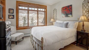A bedroom with a large bed, a chair, a dresser, and a window with a view of trees. - 4br Ski In/ski Out The Top Of Bachelor Gulch 4 Bedroom Condo by RedAwning (Avon)