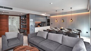 A modern living room with a grey sofa, a coffee table, and a dining area with a table set for four. - Luxury Villa Delight I – Promajna, Heated Pool (Promajna)