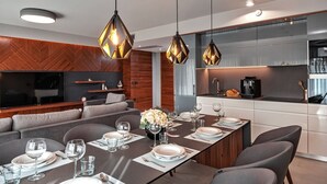 A modern dining area with a long table set for six, a built-in kitchen with stainless steel appliances, and a cozy seating area with a flat-screen TV. - Luxury Villa Delight I – Promajna, Heated Pool (Promajna)