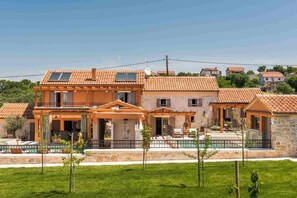 Una casa de dos pisos con techo de tejas, un balcón y una piscina.