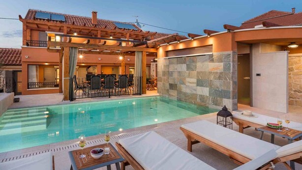 Un espace aménagé au bord de la piscine, avec des chaises longues, une table à manger et un mur en pierre.