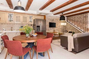Une cuisine moderne dotée d’un îlot central, de meubles de rangement intégrés, d’un grand réfrigérateur et d’un coin repas avec des chaises rouges.