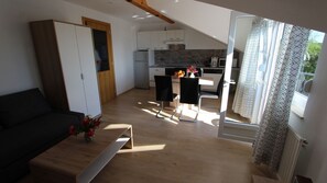 Relax in this open-plan living space with a loft-style kitchen, featuring a sofa, coffee table, and dining area.
