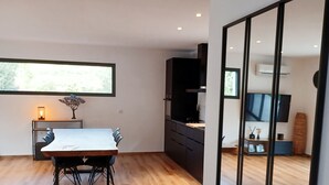 A modern kitchen with dark cabinetry, a wooden dining table, and a large window.