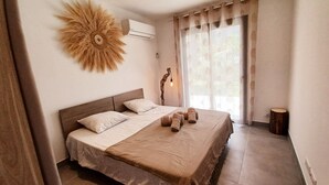 A bedroom with a large bed, a wall-mounted air conditioner, and a decorative sun-like wall piece.