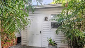 A white house with a closed door, a potted plant, and a window.