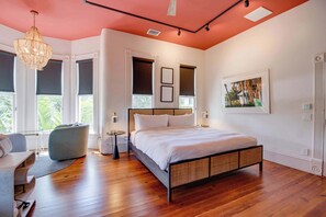 Un dormitorio moderno con una cama grande, una zona de estar con una silla y vistas al exterior.