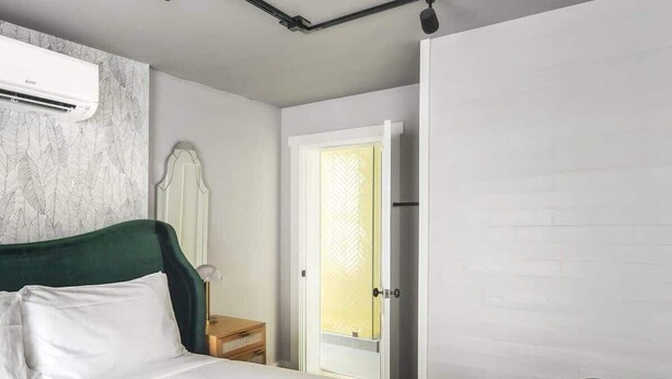 A bedroom with a bed, a nightstand, a chair, a wardrobe, and a door.