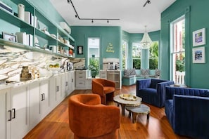 Een moderne keuken met witte kasten, een marmeren aanrecht en een eetgedeelte met oranje stoelen en blauwe banken.
