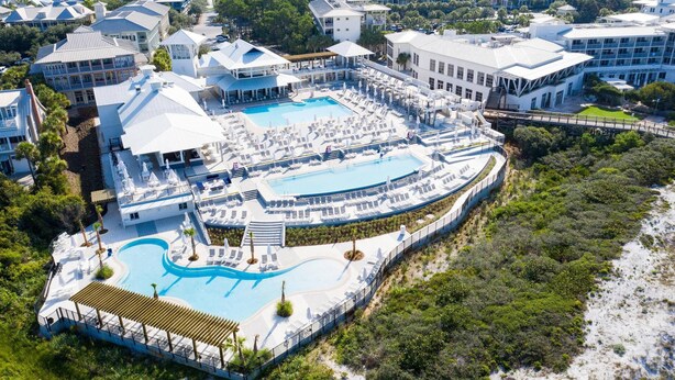 Un resort con varias piscinas, tumbonas y una zona de playa.