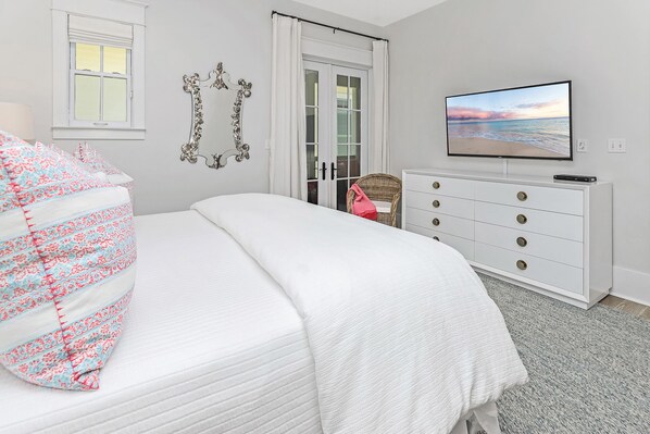 A bedroom with a bed, a dresser, a television, and a window.