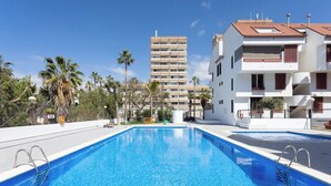 Una piscina con agua azul cristalina, rodeada de palmeras y edificios modernos.
