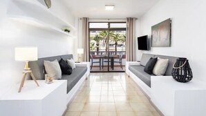 Una sala de estar moderna con dos sofás, una mesa de comedor y un televisor.
