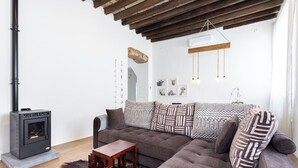 A cozy living room with a sofa, a small wooden table, a fireplace, and a hanging light fixture. - Home2Book Stunning Design House Arafo (Arafo)