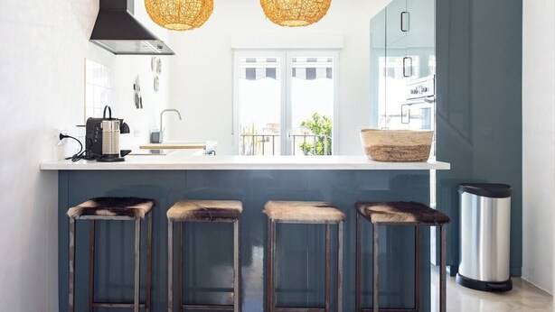 A modern kitchen with a white countertop, two hanging wicker light fixtures, a stainless steel trash can, and a window with a view of the outside. - Home2Book Stunning Design House Arafo (Arafo)