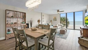 A spacious living room with a dining area, large windows offering a view of the ocean, and a ceiling fan. - Oceanfront, Pool, Beach Gear, Tennis, Smart TVs (St. Augustine)