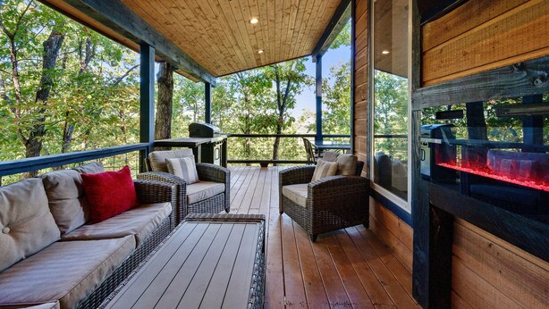 A covered outdoor seating area with wicker furniture and a grill. - Treetop Views for Miles! New, Romantic Couples Cabin (Broken Bow)