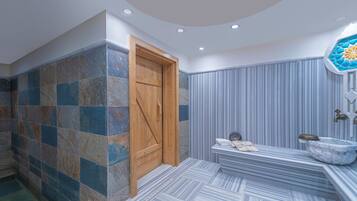 A bathroom with a wooden door, a marble sink, and a patterned floor.