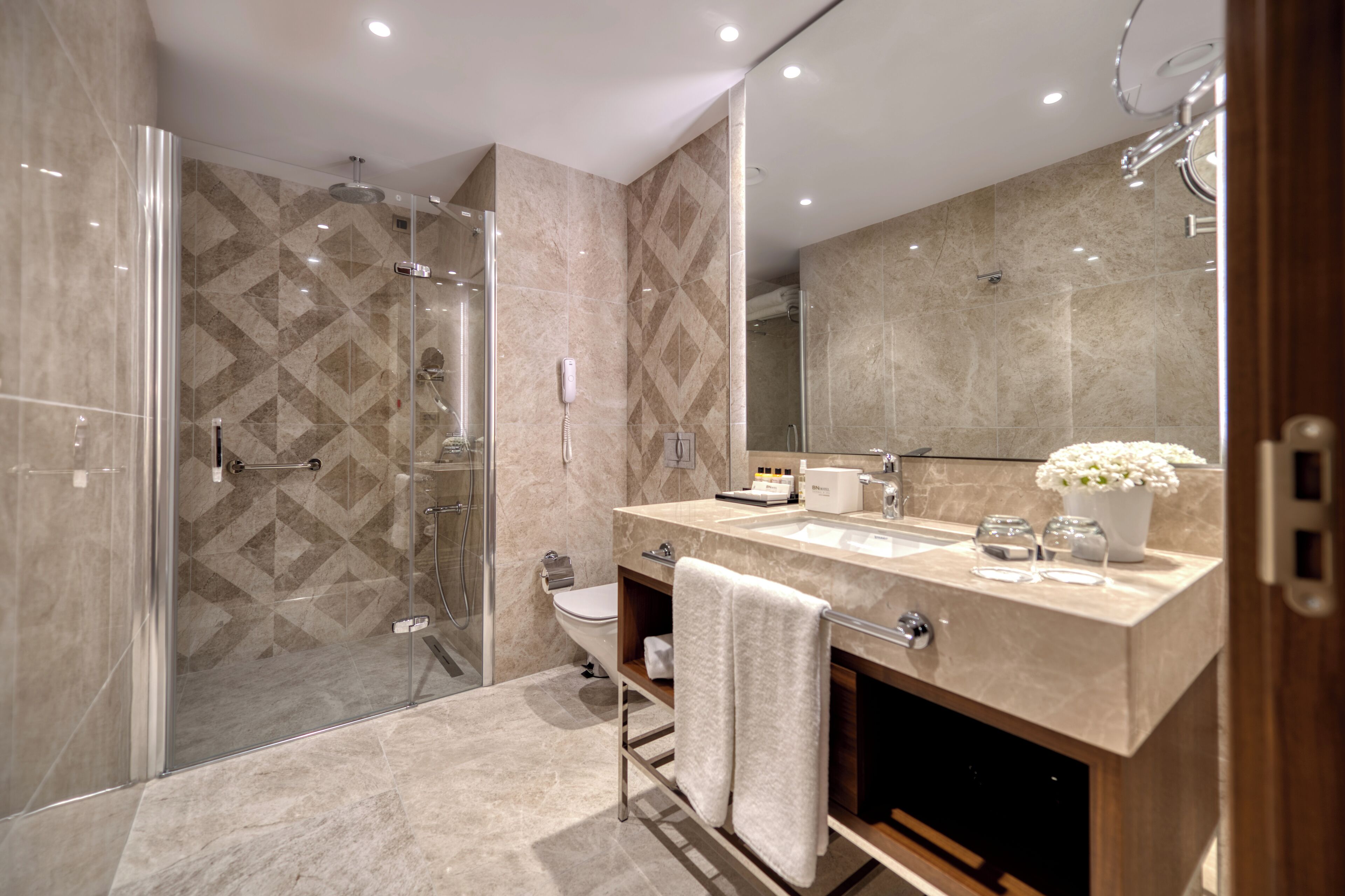 Un baño moderno con ducha a ras de suelo, inodoro y tocador con espejo.
