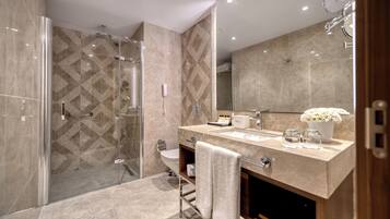 Un baño moderno con ducha a ras de suelo, inodoro y tocador con espejo.