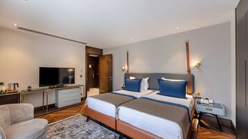 Habitación de hotel con dos camas, televisión, escritorio y una silla.