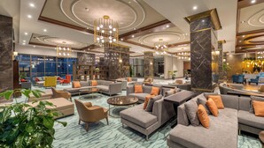 A spacious lobby with modern furniture, marble columns, and a large seating area.