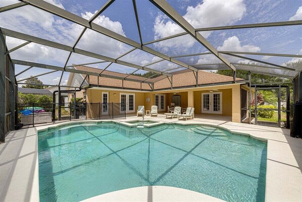 A covered swimming pool with a roof structure, surrounded by lounge chairs and a building with yellow walls. - 514-Fabulous 4 Bed in Orange Tree w/ Private Pool, Deck and Spa (Clermont)
