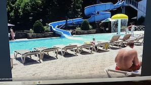 A pool area with a water slide, lounge chairs, and a small fountain.
