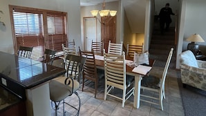 A dining area with a table and chairs, a kitchen area with a counter, and a staircase leading to another level.