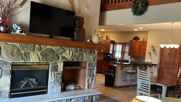 A spacious living area with a stone fireplace, a television, and a dining area with wooden furniture.
