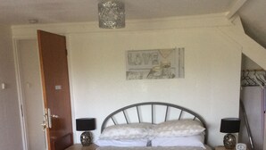 Une chambre à coucher comprenant un lit, des tables de chevet, une chaise, une horloge murale et un objet décoratif.