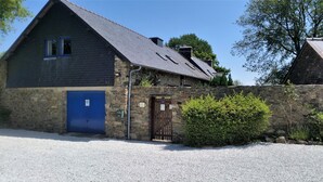 Un bâtiment en pierre avec une porte bleue et une allée gravillonnée.