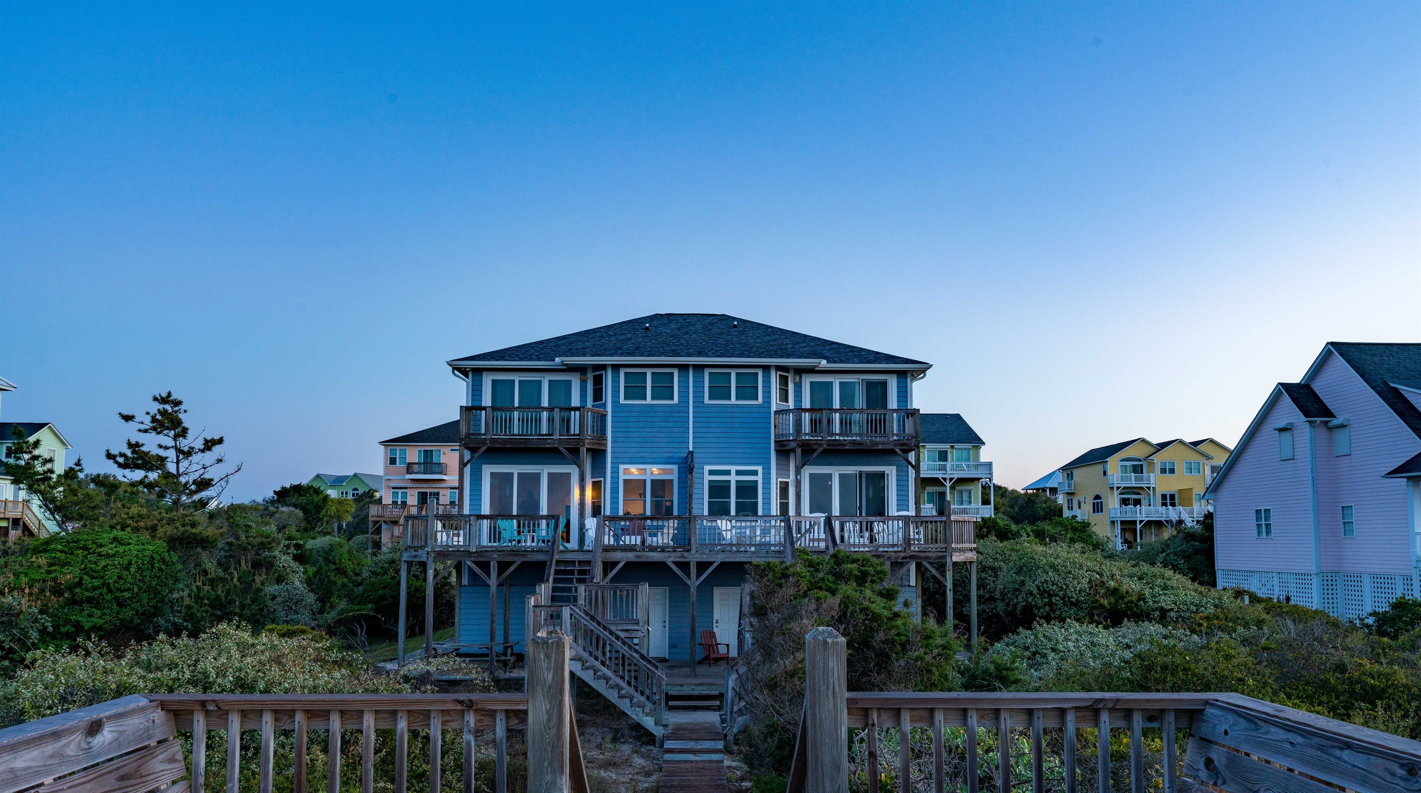 A multi-story house with a balcony, a wooden deck, and a staircase leading to the entrance.