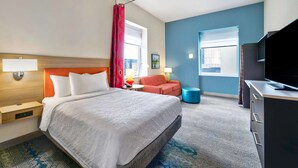 Une chambre d’hôtel avec un grand lit, un bureau, une télévision et une fenêtre avec des rideaux.