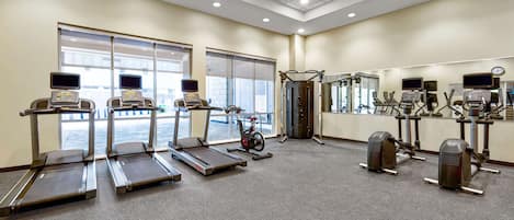 A gym with treadmills, stationary bikes, and elliptical machines.