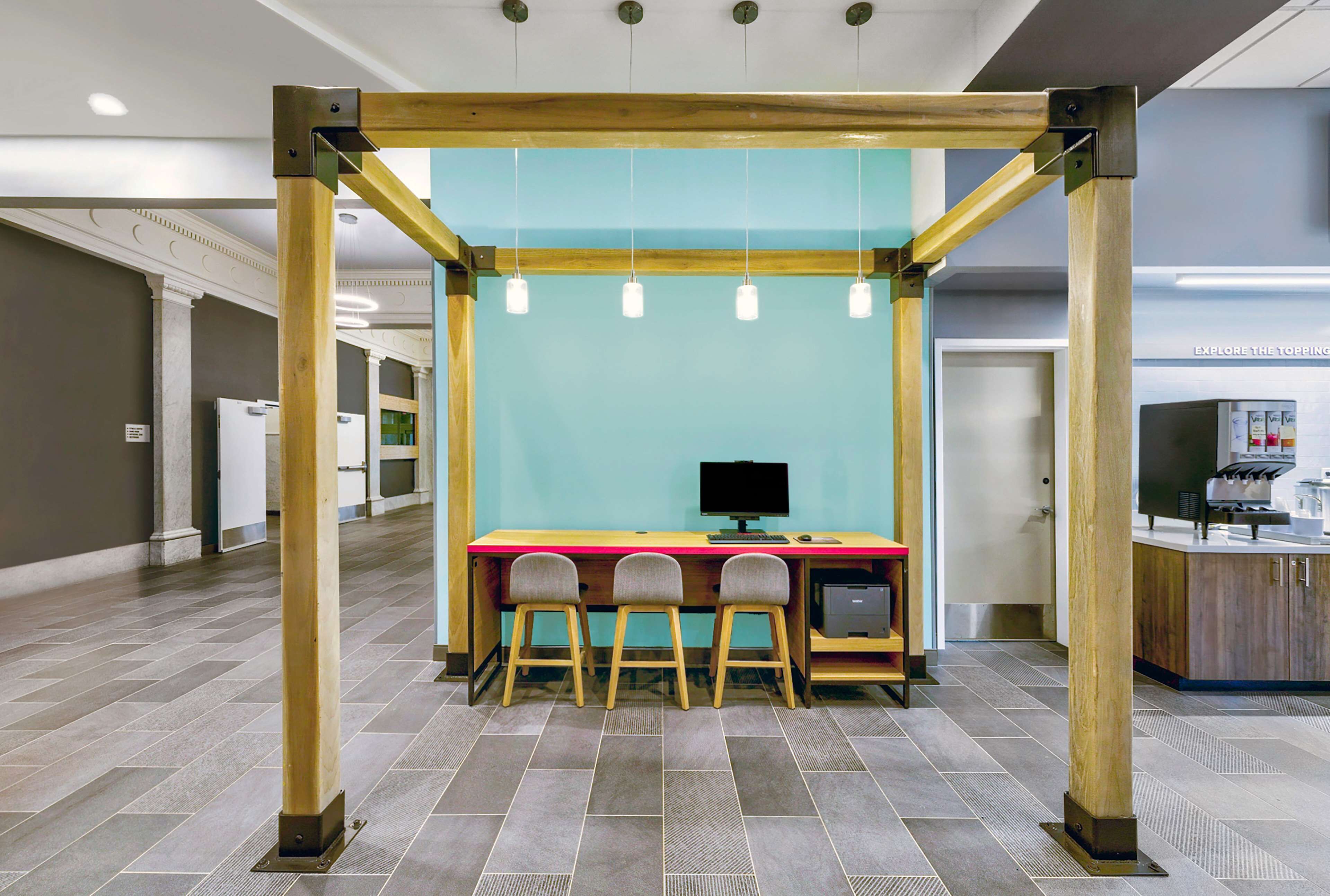 Un espace de travail moderne doté d  ’une structure en bois, d’un mur de couleur turquoise et d’un bureau avec trois chaises.