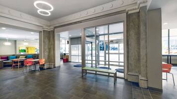 A spacious lobby with a central seating area, a glass door entrance, and a modern ceiling design.