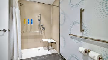 A modern bathroom with a shower, toilet paper, and toiletries.