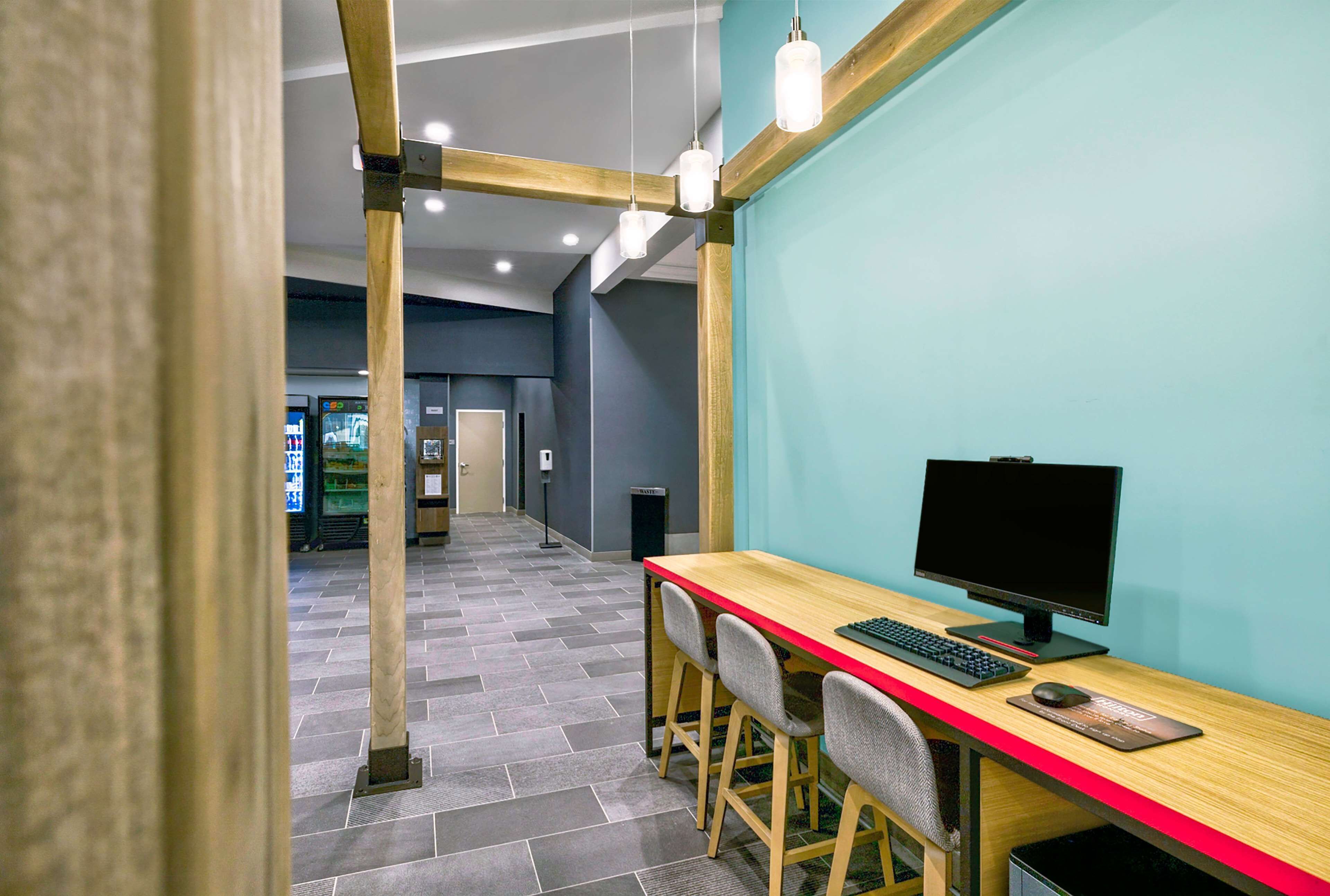 A modern office space with a wooden desk, two chairs, a computer monitor, and a keyboard.